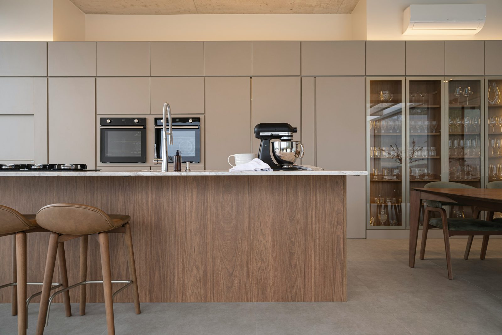 Cocina con gabinetes lisos color greige e isla de nogal