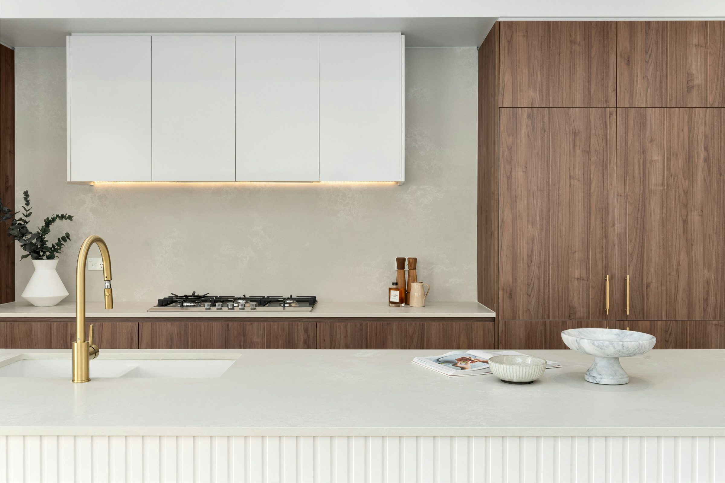 Cocina integral con gabinetes altos blancos lisos y gabinetes de nogal